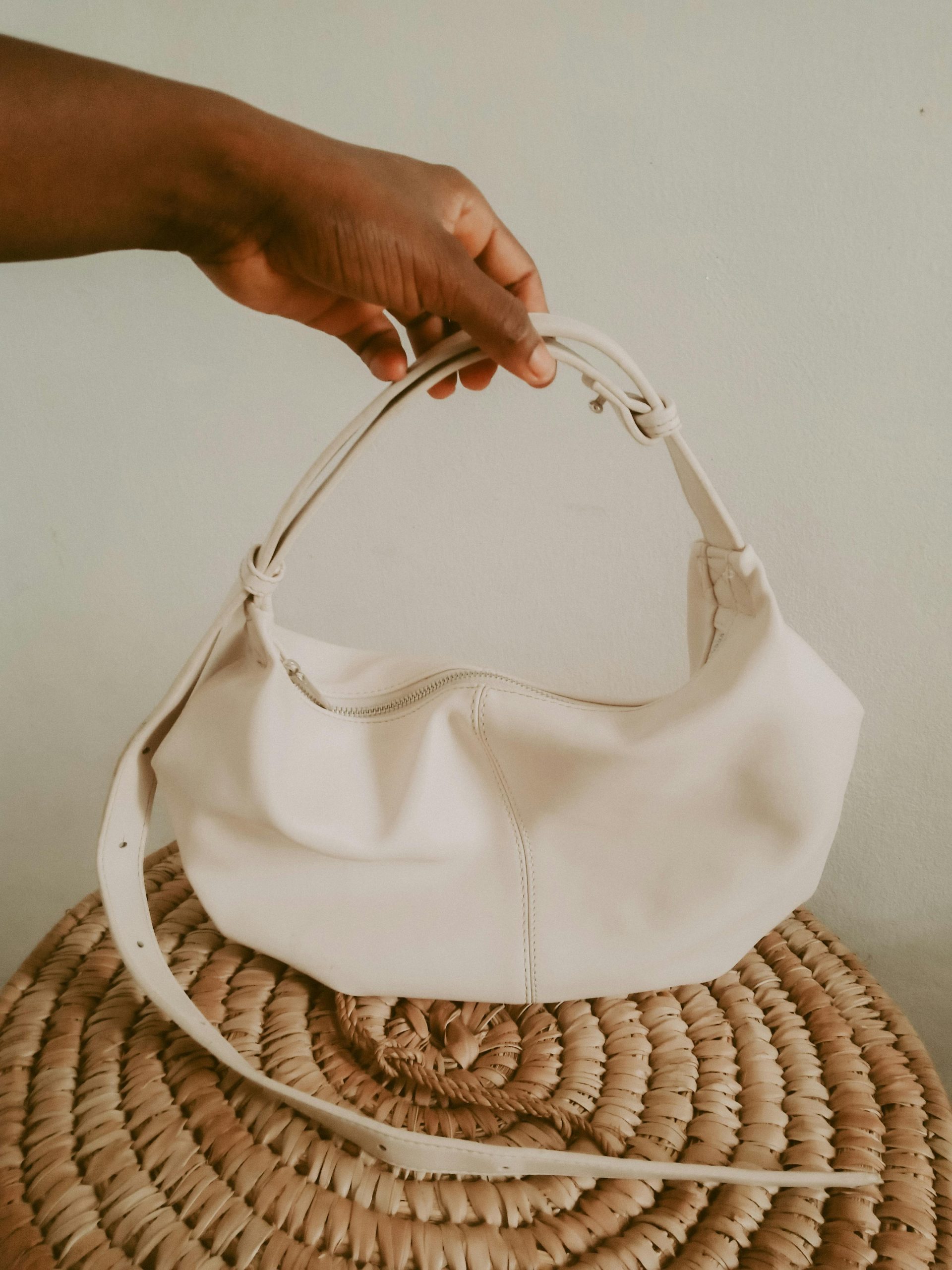 Elegant white handbag held by hand, showcasing minimalist design and fashion.