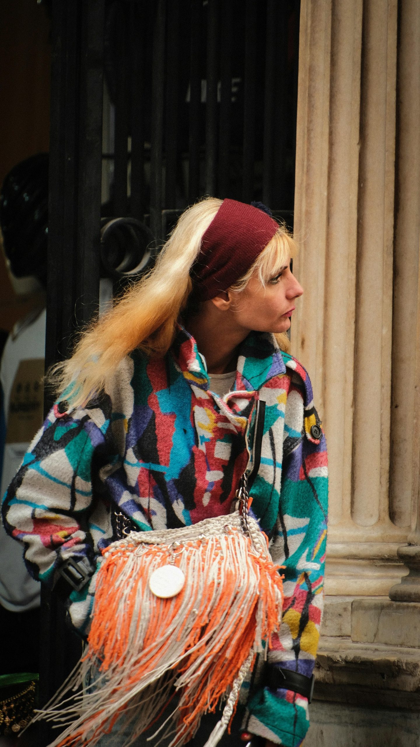 A fashionable woman wearing a colorful jacket in an urban setting, showcasing modern street style.