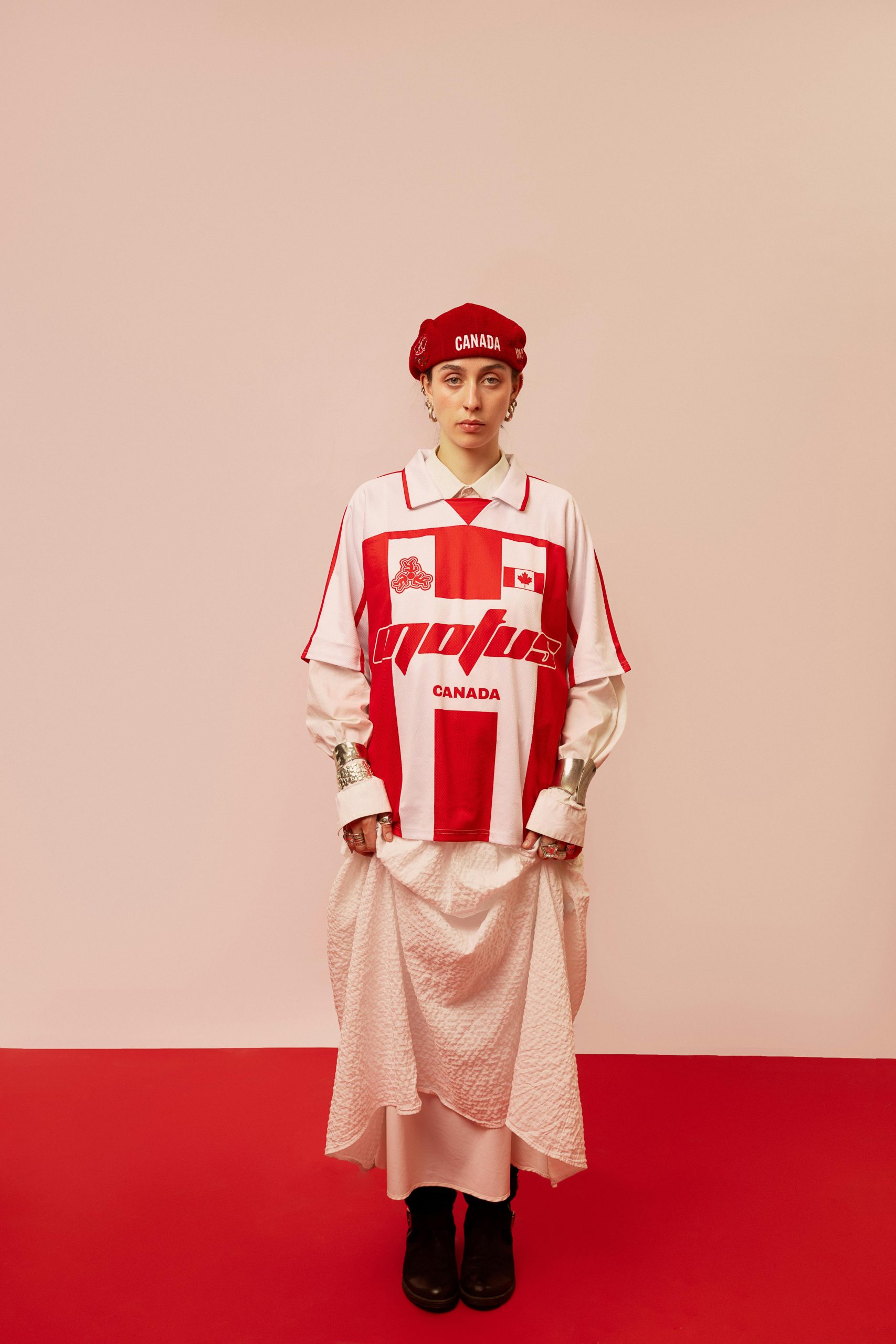 Model in red and white clothing with Canada theme, posed indoors on red background.