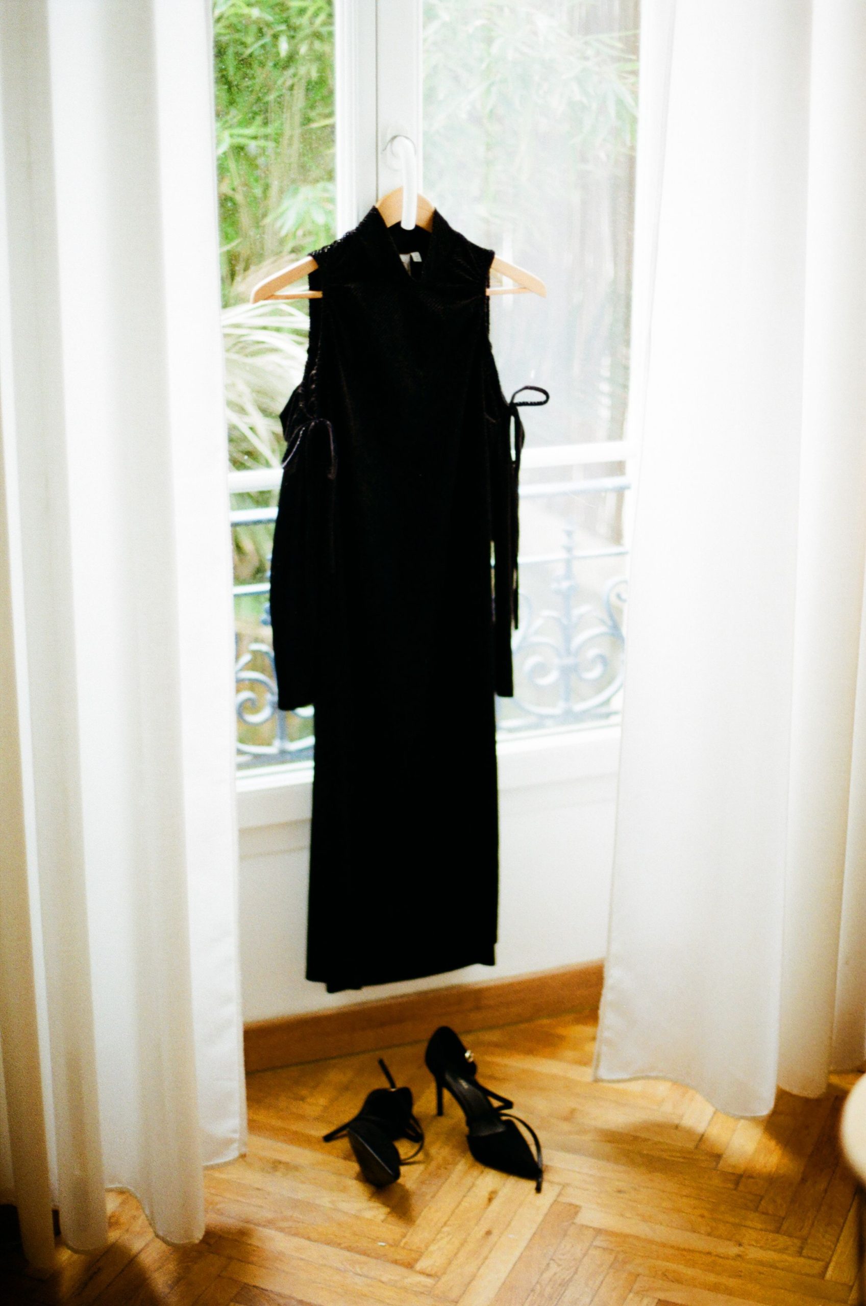 Elegant black dress and heels by a window in Nice, France, capturing timeless fashion